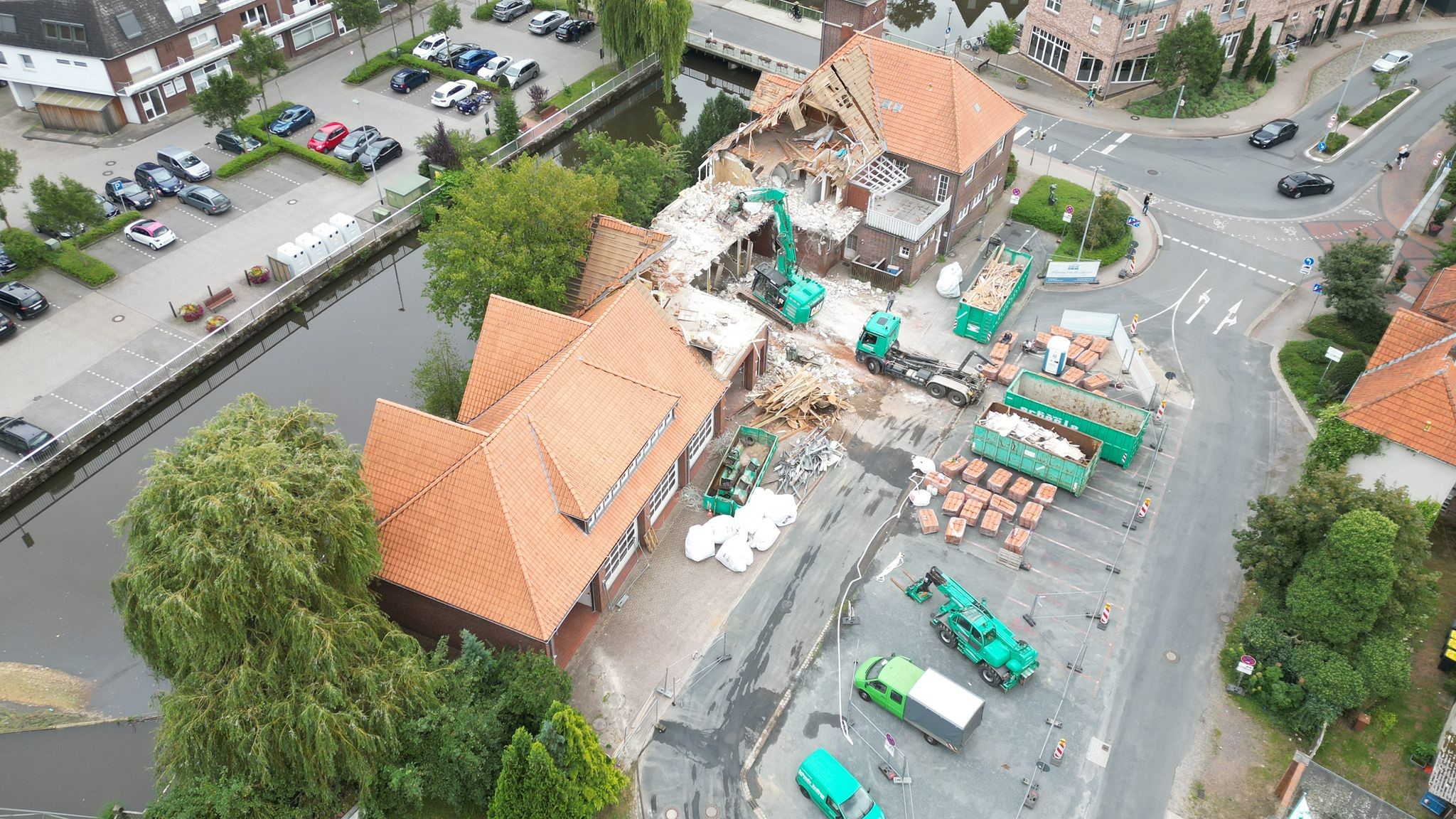 Luftaufnahme einer Baustelle mit abgerissenem Ziegelgebäude und Baufahrzeugen