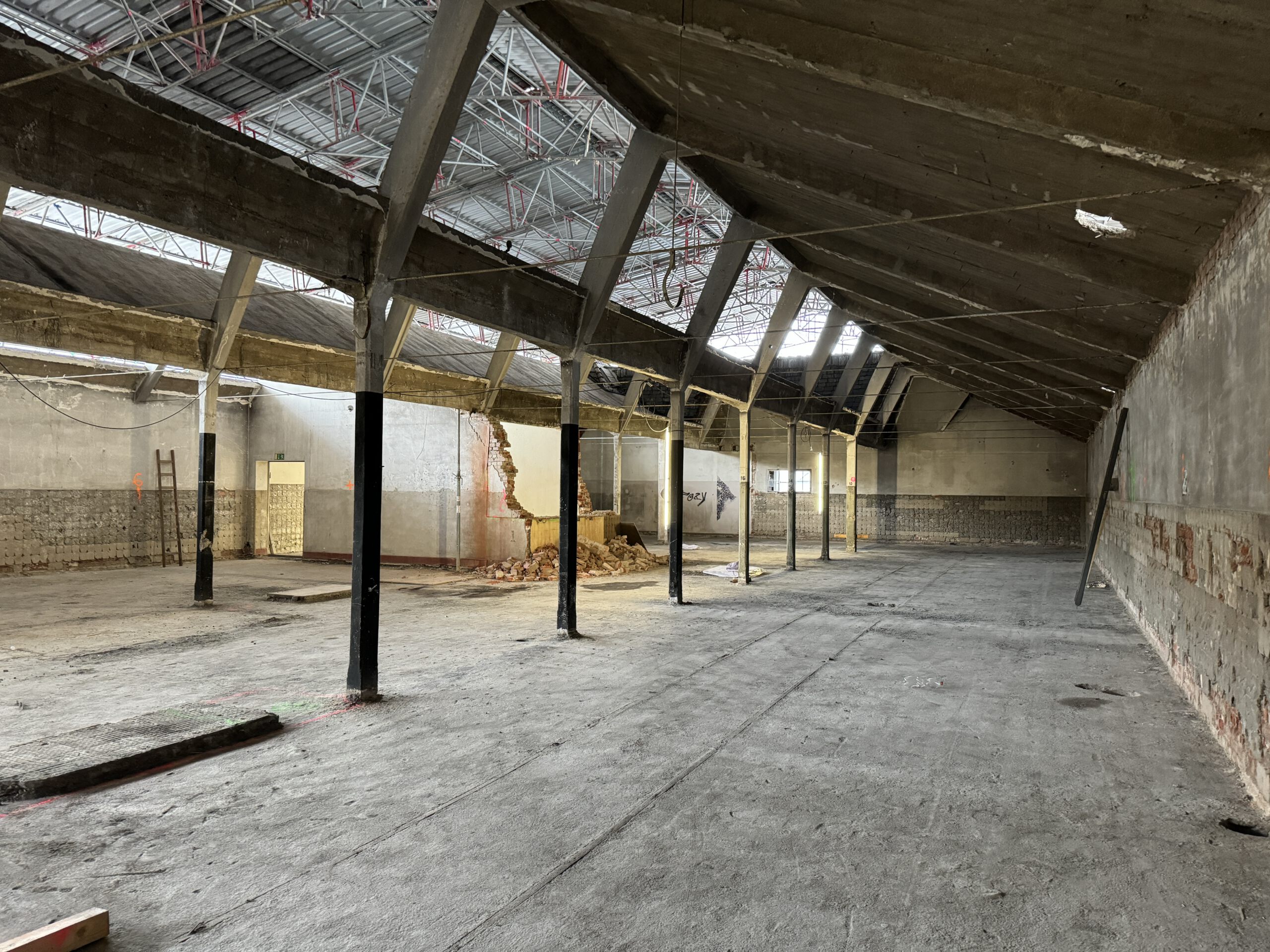Renovierung eines großen Innenraums mit freiliegenden Trägern und Betonfußboden